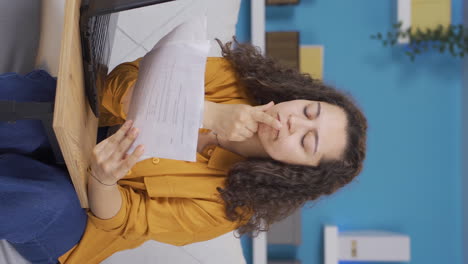 Vertical-video-of-The-young-woman-looking-at-the-documents-is-thoughtful.